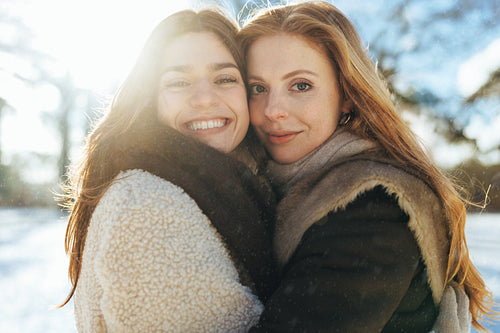 Three women celebrate friendship with a hug in snow