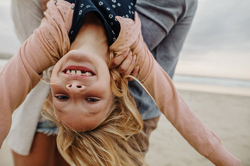 Girl playing with her parents at the beach