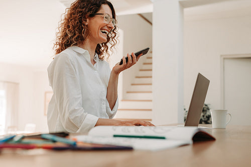 Happy businesswoman talking over phone at home