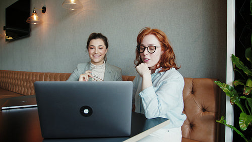 Business women talking and watching a slideshow on a laptop