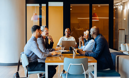 Group discussing strategies in an office with laptops and cheerful interaction