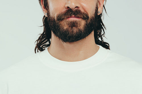 Man with a beard and perfect skin standing in a studio