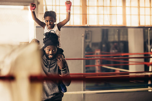 Trainer carrying a boxer kid on his shoulders in the gym