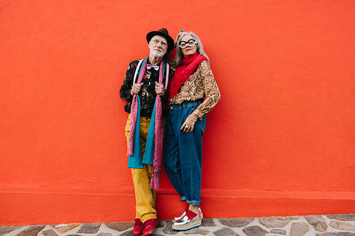 Mature couple standing together against a red wall