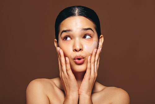 Soothing under eye treatment with a gel patch, sticking a cosmetic patch on her face
