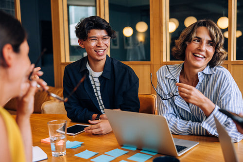 Two smiling adults engaging in a casual conversation in an office setting