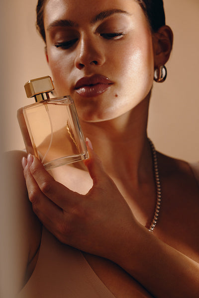 Woman holding luxury perfume bottle near her face