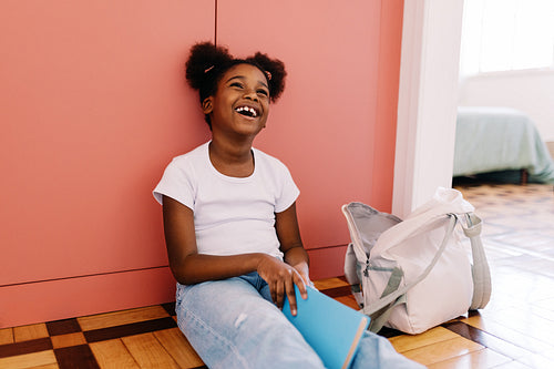 Young student with afro hair laughing while doing homework at home