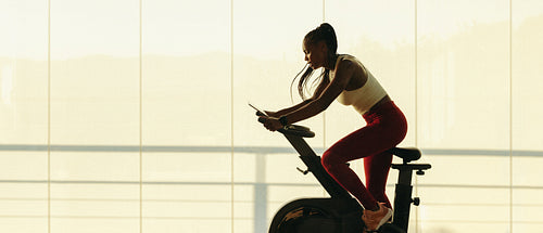Fitness training in the gym: Black woman stays on track with online cycling class