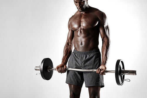 African sportsman exercising with barbell