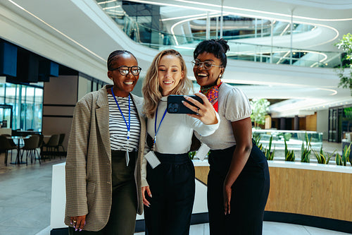 Friendly team of diverse coworkers taking a selfie together in a modern corporate environment