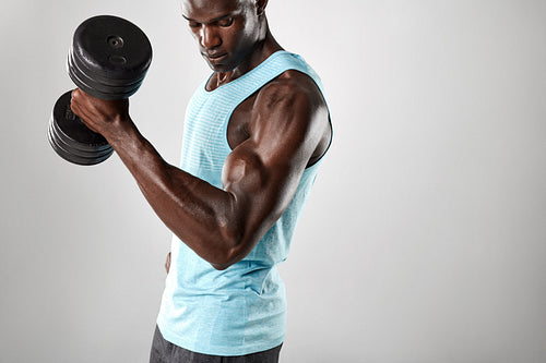Fit and young man working out with heavy dumbbell