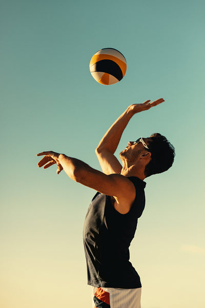 Jumping athlete playing beach volleyball during a summer tournament