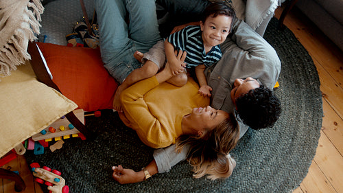 Enjoying play time with mom and dad, little boy laughs as his parents tickle him
