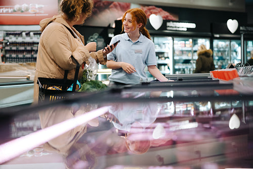 Customer asking supermarket employee for help finding a food item