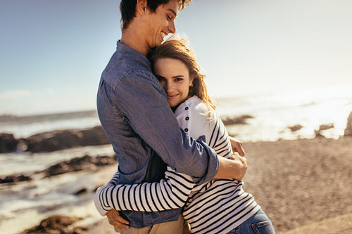Happy couple hugging each other standing at the beach