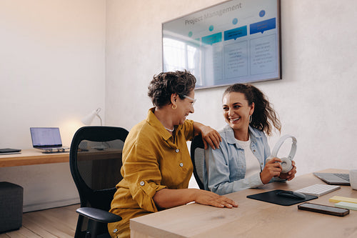 Two women sharing a moment in a modern office workspace