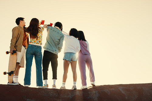 Group of friends drinking and celebrating outdoors during sunset