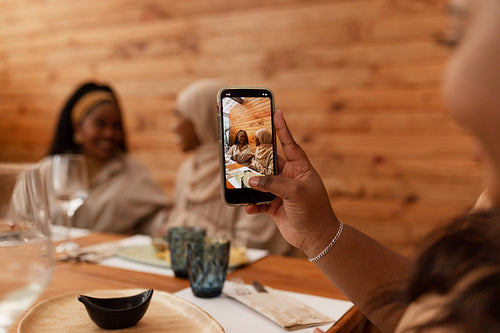 Millennial woman taking a picture of her friends in a restaurant