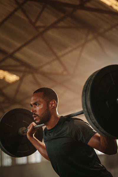 Man doing squats with barbell in gym