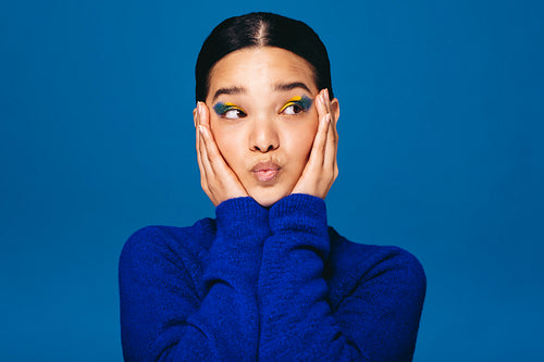 Young woman embracing her face while wearing makeup in a studio