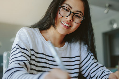 Smiling girl with eyeglasses studying at home