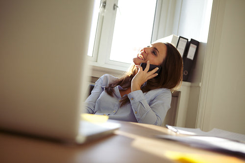 Beautiful businesswoman in home office talking on mobile phone
