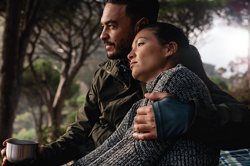 Young couple resting outdoors with a cup of coffee