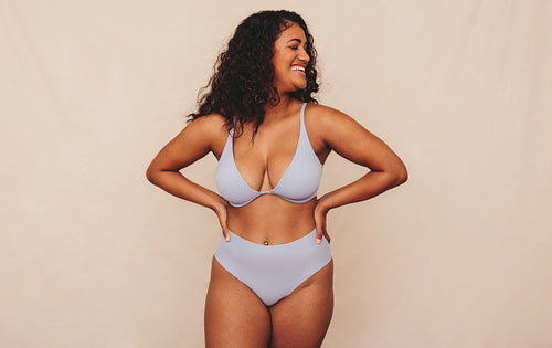 Smiling young woman embracing her natural body in a studio