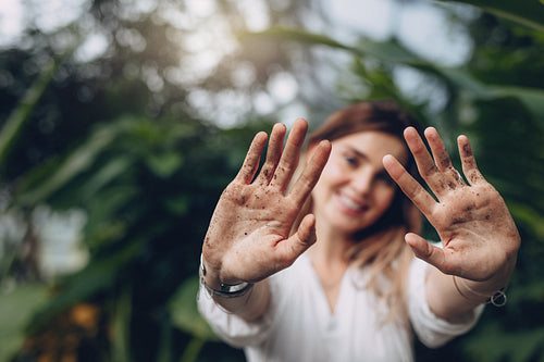 Gardener showing her dirty palms at greenhouse