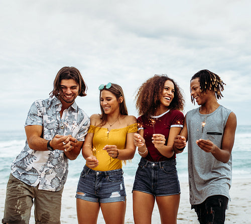 Multi-ethnic friends enjoying at beach with sparklers
