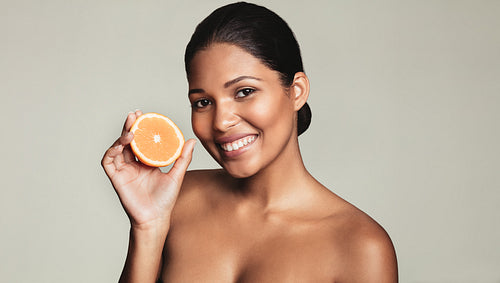 Beautiful young woman holding an orange