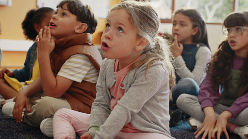 Multiethnic elementary school children actively engaging in a lesson led by their teacher in a classroom