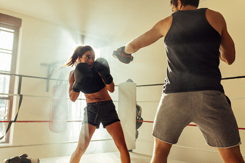 Young female boxer steps back as opponent strikes