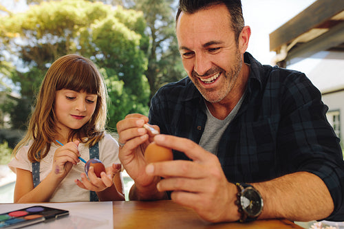 Father and daughter putting paint on easter eggs