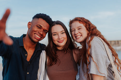 Three diverse friends smiling at the camera