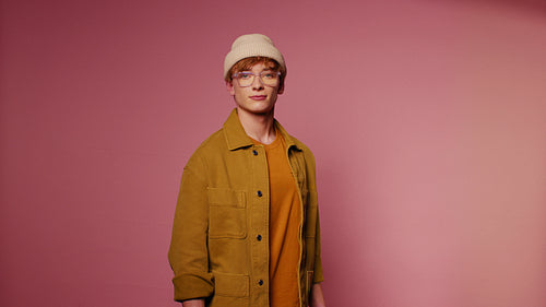 Young man posing in a studio with a pink background