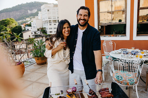 Latin couple smiling at a Brazilian churrasco on a sunny terrace