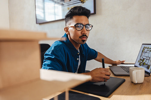 Focused architect working on designs in a modern workspace with a tablet