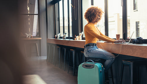 Female tourist using a laptop sitting at a restaurant