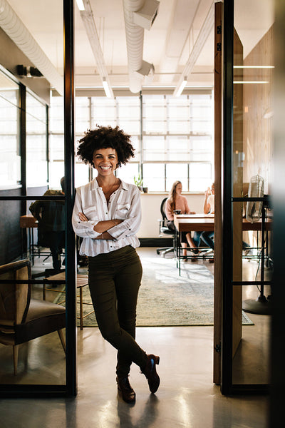 Successful young woman leaning to office doorway
