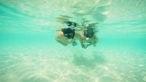 Snorkeling adventure of a couple in clear turquoise waters on a sunny tropical holiday