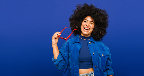 Stylish young woman smiling happily while holding sunglasses
