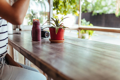 Smoothie jar on a table beside a flower pot