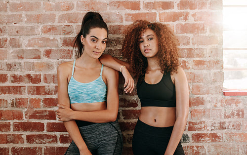 Sporty young woman standing against wall