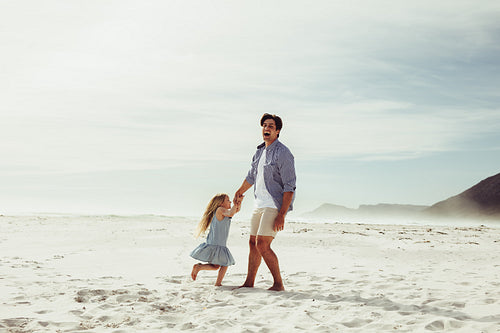 Father and daughter having fun playing on the beach.