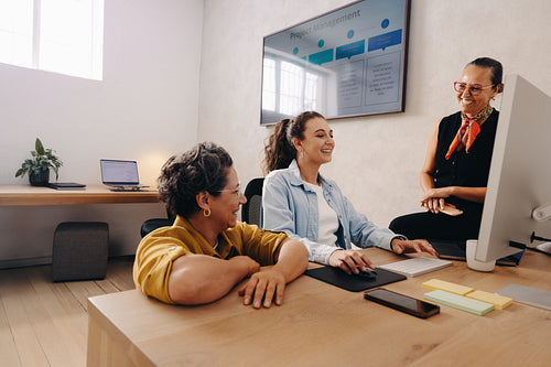 Three women collaborating in a modern office setting on a work project