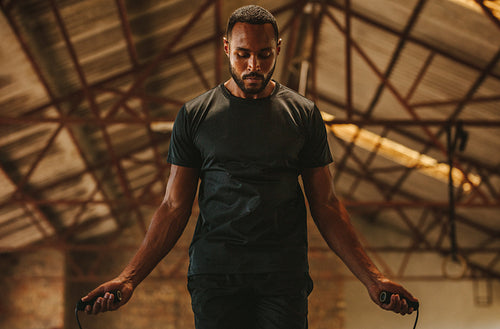 Fitness man skipping ropes at cross workout space