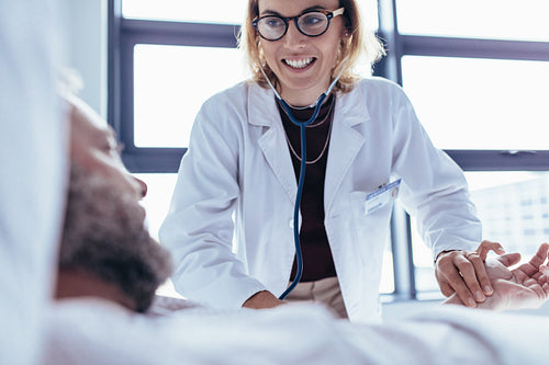 Female doctor examining male patient in hospital room