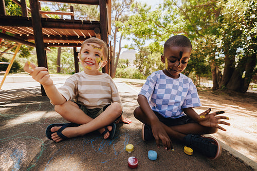 Two children enjoying outdoor painting activities on a sunny day